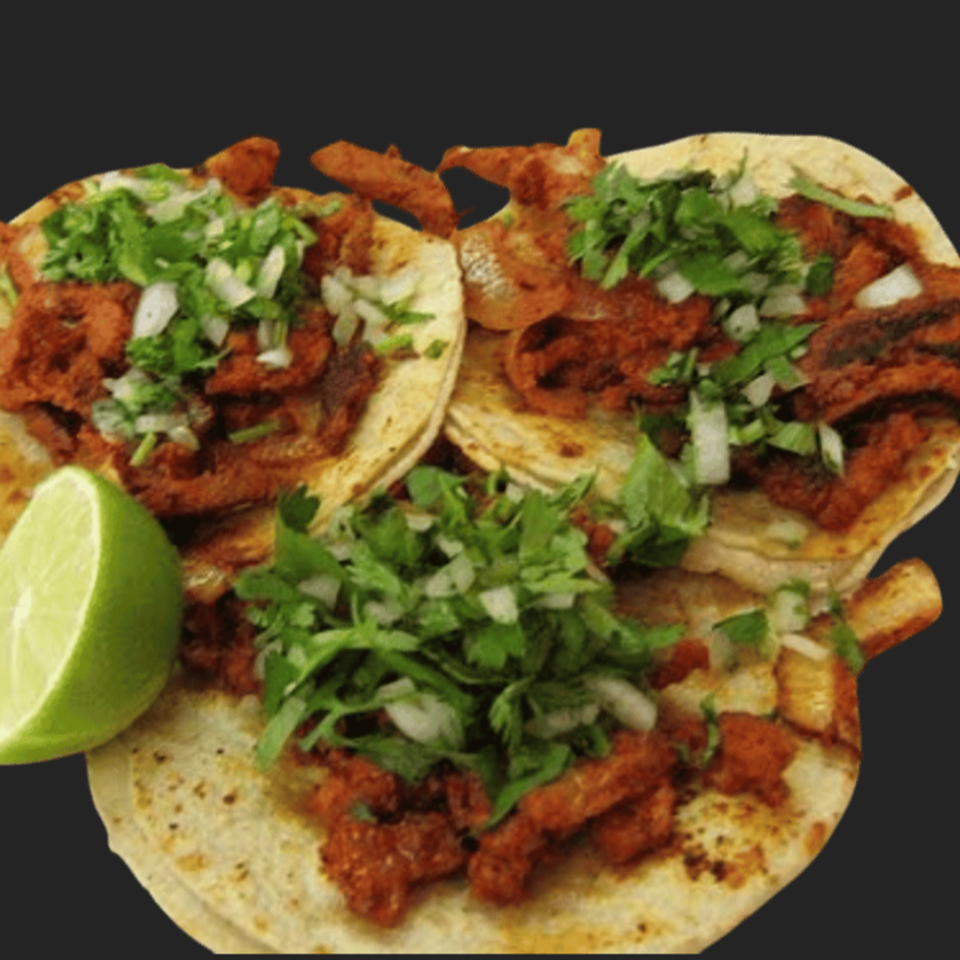Three soft tacos filled with seasoned grilled meat, chopped cilantro and onions, served with a lime wedge.